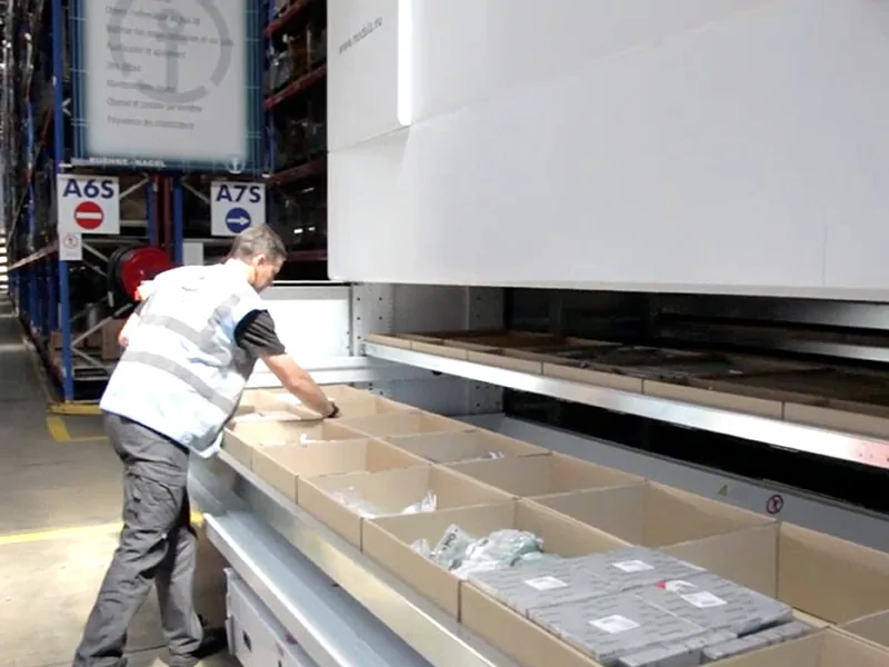 Operador de Kuehne+Nagel en la bahía de un Modula con los contenedores de pedido al frente; fotografía de la ficha oficial del caso